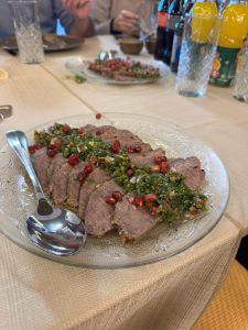 "פרוסות בשר סינטה צלוי עם רוטב עשבי תיבול ורימונים מוגשות על צלחת חגיגית באירוע"