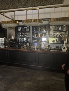 בר יוקרתי באולם אירועים קטן בירושלים עם מדפי אלכוהול מוארים, תאורה תלויה מרשימה ועיצוב מוקפד שמתאים לאירועים אינטימיים בעיר